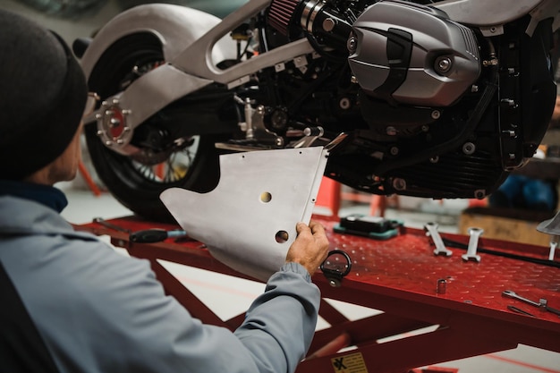 Man fixing a motorcycle in a modern workshop