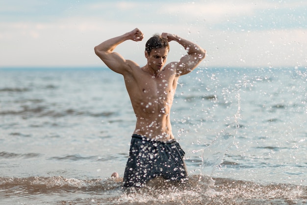 Foto gratuita uomo che flette i suoi bicipiti in acqua