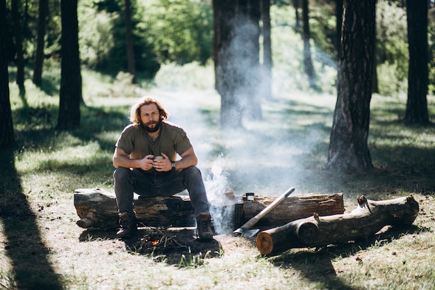 Man in forest with tea by fire