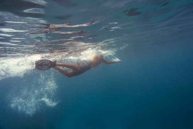 Foto gratuita uomo in apnea con pinne sott'acqua