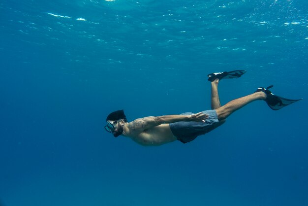水中で足ひれを持ってフリーダイビングする男