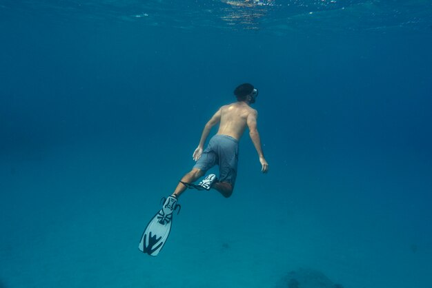 水中で足ひれを持ってフリーダイビングする男