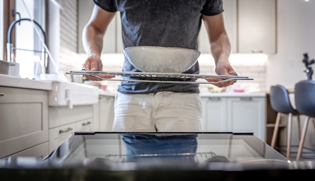 皿を持った開いた食器洗い機の前の男。