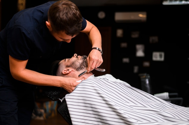 Man getting a beard trim with a razor