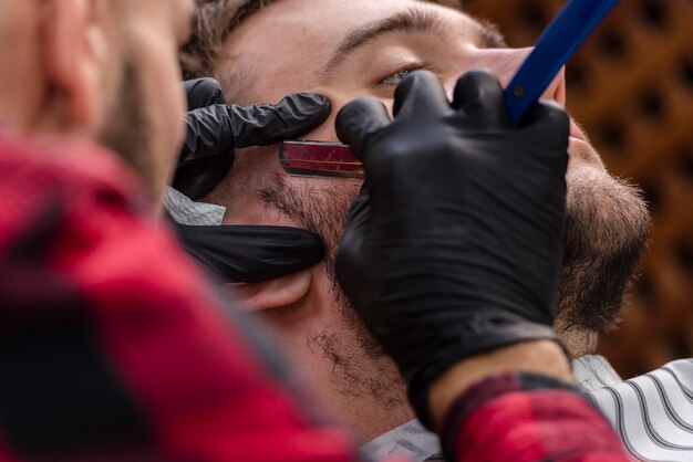 Man getting a beard trimmed with a blade