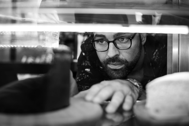 Free photo man getting cake out of the display fridge