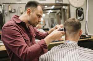 Free photo man getting a haircut at a barbershop