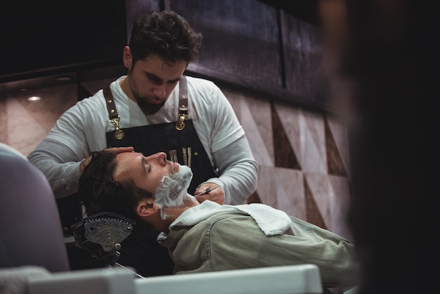 Free photo man getting his beard shaved with razor