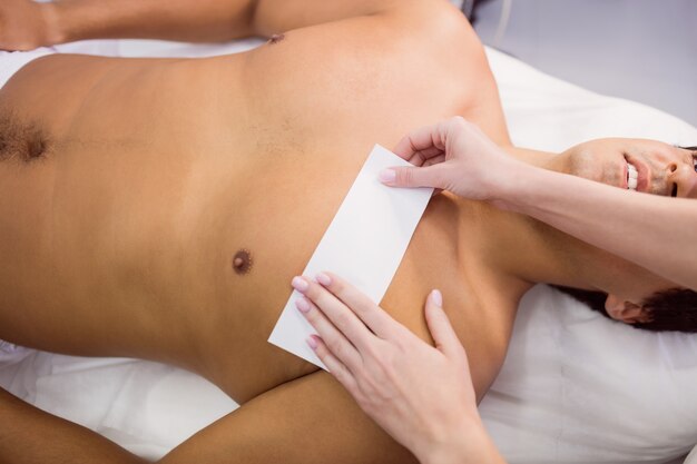 Man getting his chest waxed with wax strip