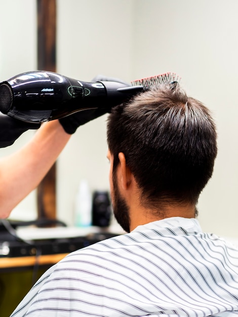 Foto gratuita uomo che ottiene i suoi capelli asciugati con un essiccatore