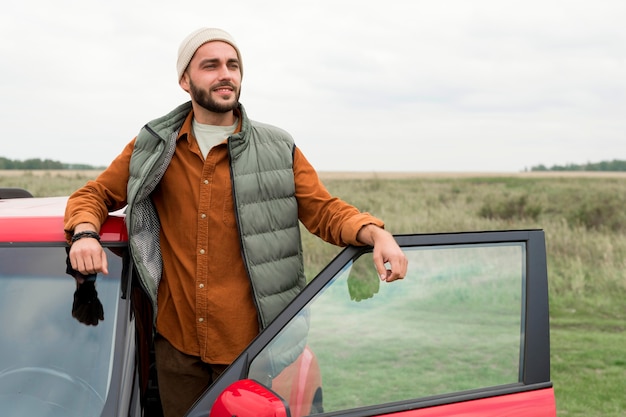 Foto gratuita uomo che esce dall'auto in natura