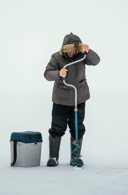 Free photo man getting ready for fishing in frozen lake