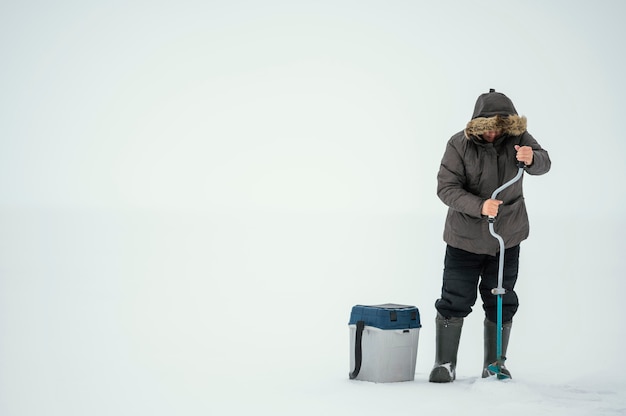 凍った湖で釣りの準備をしている男