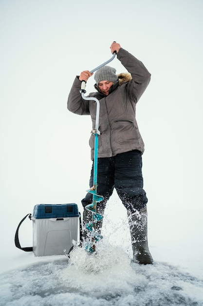 Free photo man getting ready for fishing in frozen lake