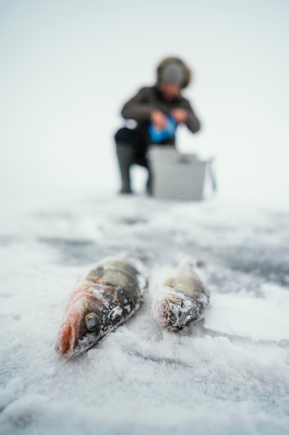 凍った湖で釣りの準備をしている男