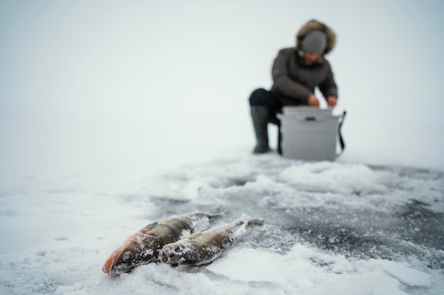 凍った湖で釣りの準備をしている男