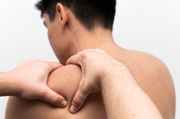 理学療法士から痛みのために肩のマッサージを受けている男性