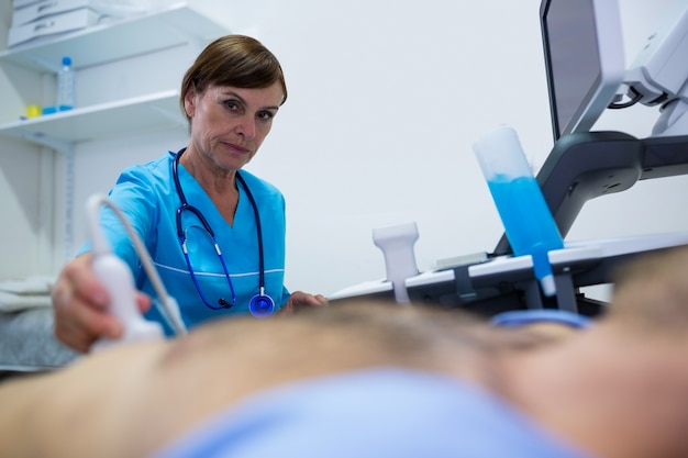 Free photo man getting ultrasound of a abdomen from doctor