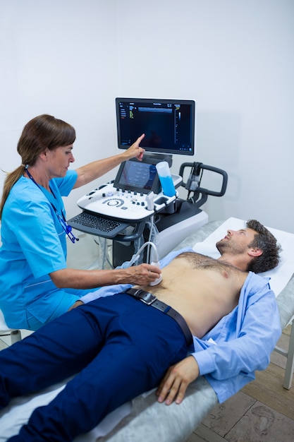 医者から腹部の超音波検査を受ける男性