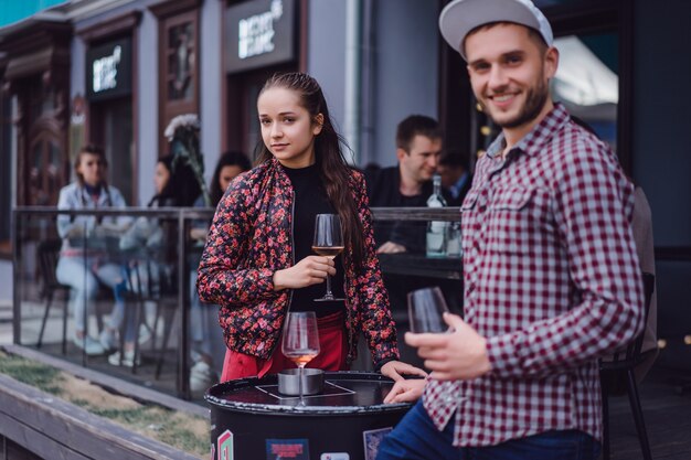 A man and a girl are drinking wine on a summer terrace in a street cafe. Stylish couple drinking wine in cafe