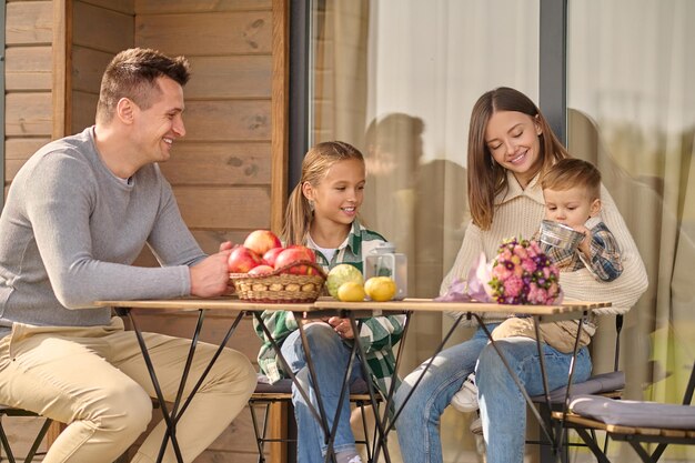 Man girl and woman looking at child sitting at table