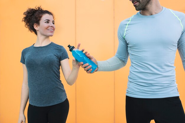 Man giving drink to fit woman