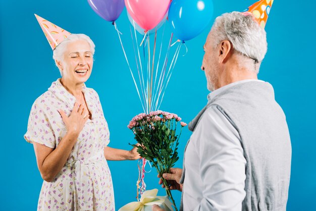 Uomo che dà fiore e regalo di compleanno a sua moglie