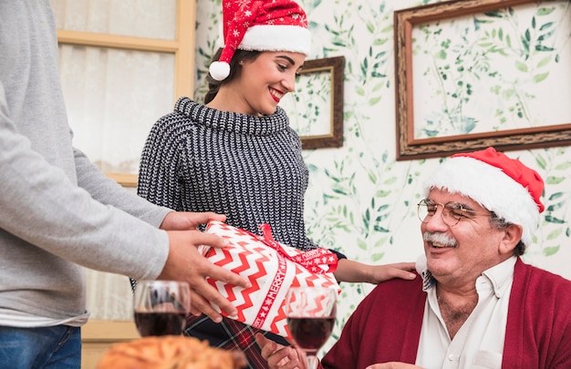 Equipaggi dare il contenitore di regalo all'uomo anziano in cappello di santa