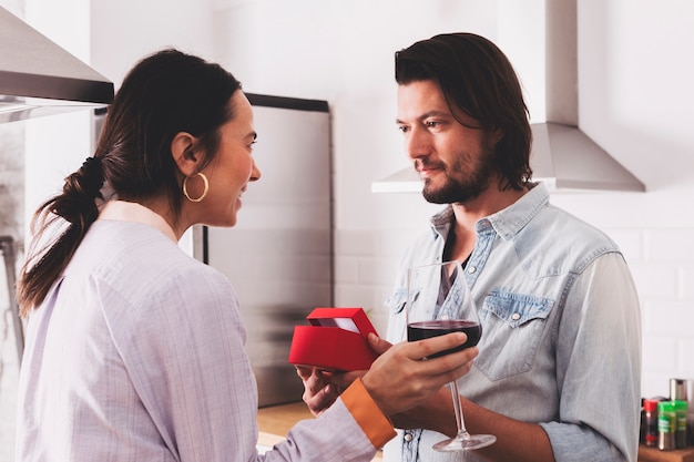 man giving gift box to woman in kitchen 