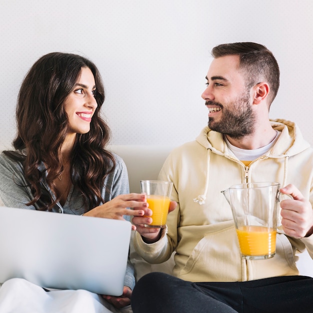 Man giving juice to woman at laptop