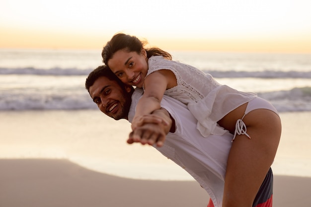 Free Photo  Man giving piggyback ride to woman on the beach