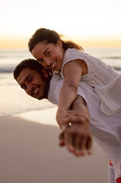 Free Photo  Man giving piggyback ride to woman on the beach