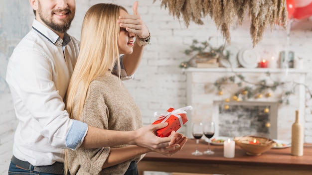 Man giving present to woman making surprise