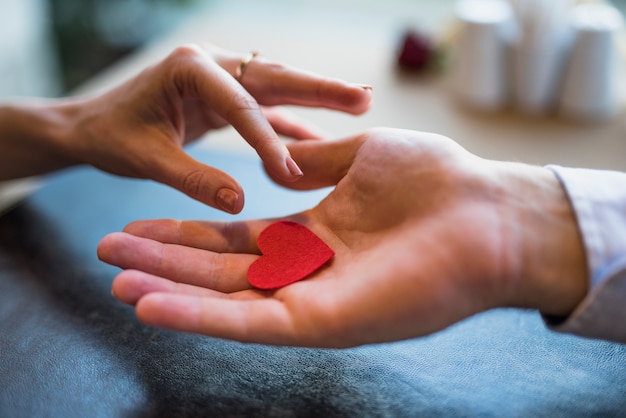 Man giving red ornament heart to woman