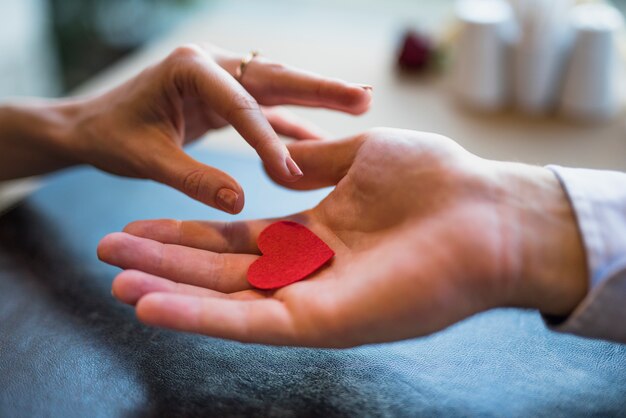 Man giving red ornament heart to woman