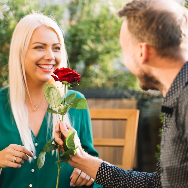 Foto gratuita uomo che dà rosa rossa alla sua ragazza all'aperto