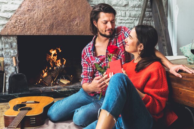 Man giving red rose to woman on floor 