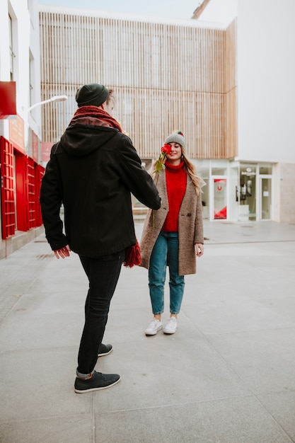 Free photo man giving rose to girlfriend on street