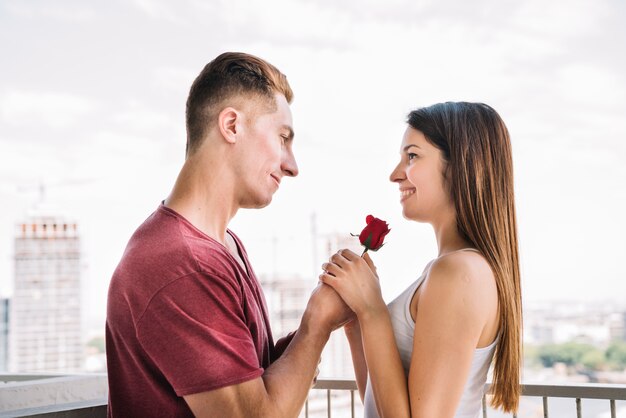 Man giving rose to woman on balcony