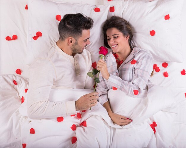 Man giving rose to woman in bed 