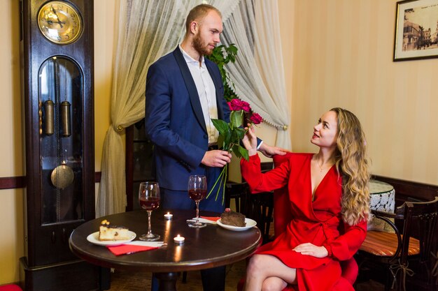 Man giving roses bouquet to woman in restaurant 