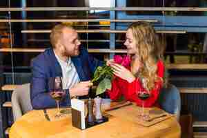 Free photo man giving roses bouquet to woman at table