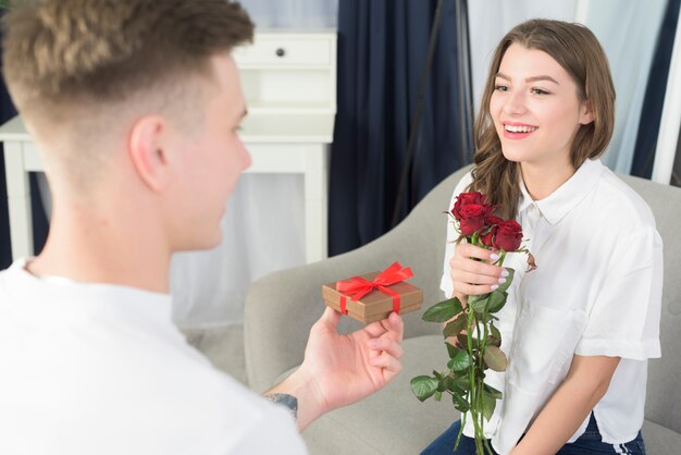 Man giving small gift box to happy woman 