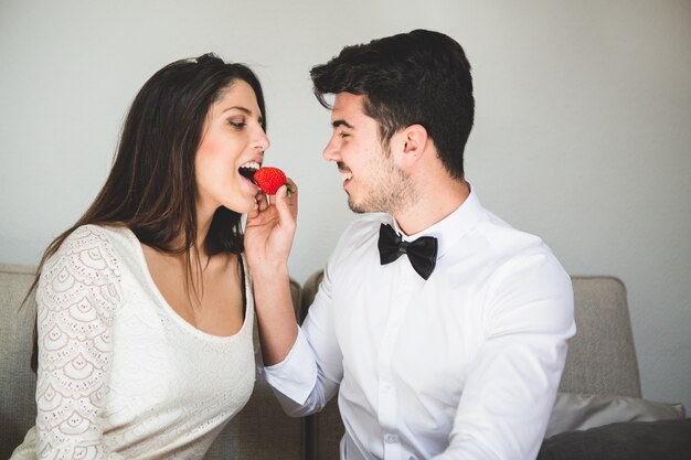 Man giving a strawberry to his wife's mouth