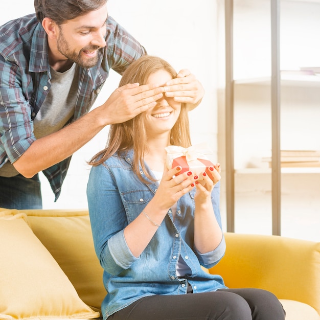 Foto gratuita uomo che dà regalo a sorpresa alla ragazza che copre i suoi occhi