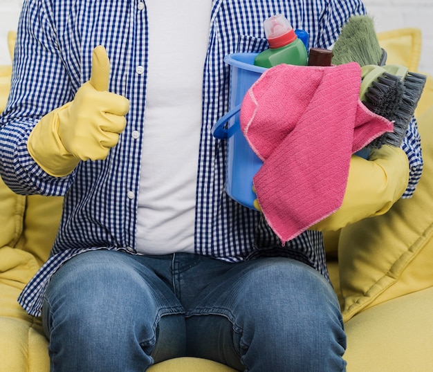 Man giving thumbs up while holding bucket with cleaning products