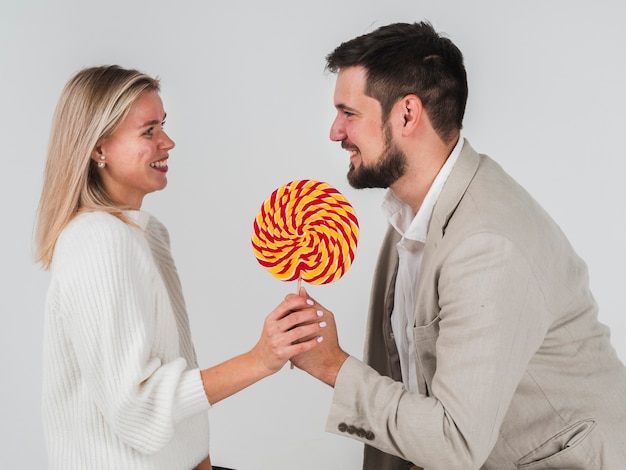 Free photo man giving woman lollipop for valentines