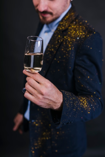 Foto gratuita l'uomo in polvere glitterata con bicchiere di champagne