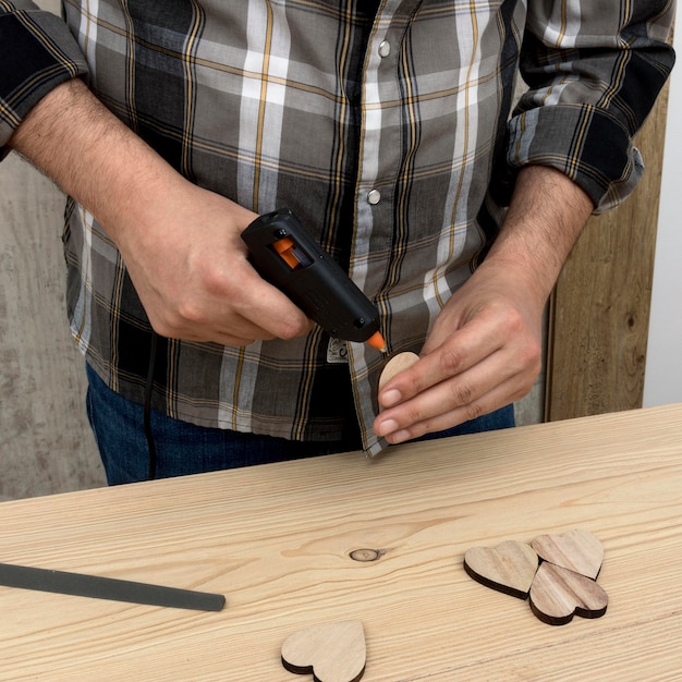 Free photo man glueing a piece of wood