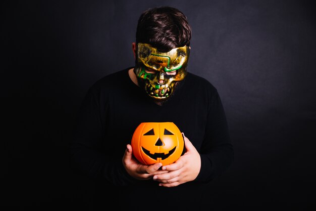 Man in gold mask holding pumpkin